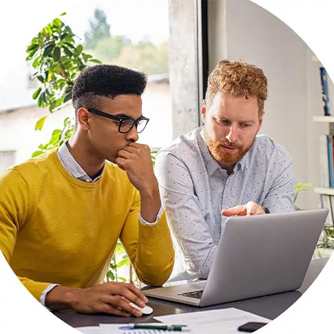 Two men are discussing work on a laptop